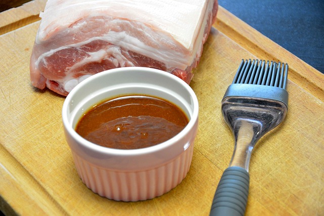 Barbecue Sauce A cup of barbecue sauce, with meat behind it, and a brush next to the sauce.